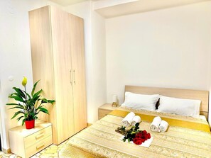 Una habitación de hotel con cama, mesita de noche, armario y una planta en maceta.