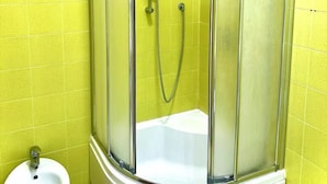 Une salle de bain avec une douche à parois de verre, un lavabo blanc et des carreaux jaunes.