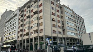 Un immeuble à plusieurs étages doté d’une architecture moderne, avec des balcons et une entrée au niveau du sol.