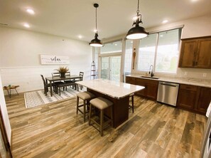 Una cocina con una isla central, armarios de madera y un comedor con mesa y sillas.