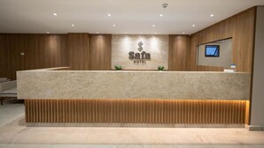 Un espace d’accueil doté d’un comptoir en marbre, de lambris en bois, d’une enseigne indiquant « Hôtel Safa » et d’un téléviseur fixé au mur.