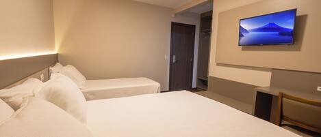 Une chambre d’hôtel avec deux lits, un téléviseur fixé au mur et un bureau.