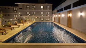 Une piscine avec des chaises longues et un bâtiment en arrière-plan.