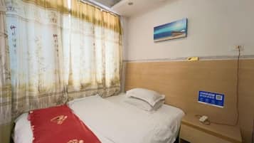 A hotel room with a bed, a nightstand, a painting on the wall, and a window with curtains.