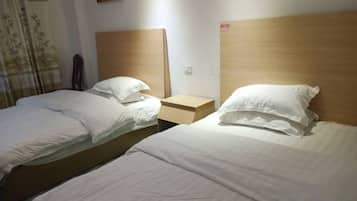 A hotel room with two single beds, wooden headboards, and a nightstand with a lamp.
