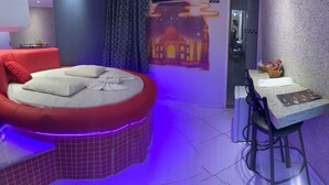 A modern room with a red sofa, a small dining area with stools, and a wall-mounted TV. - Hotel 1001 Prime (Ceilandia)
