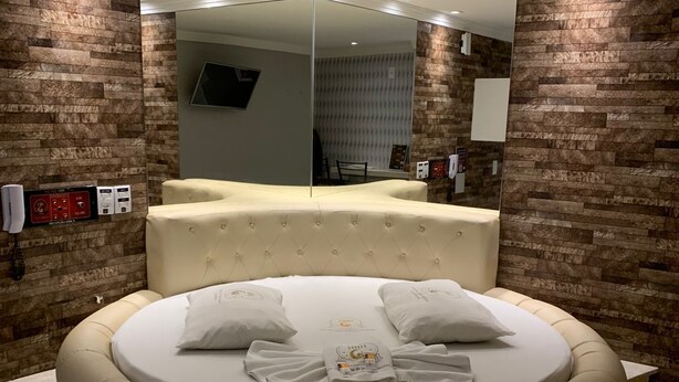 A circular bed with a beige headboard and pillows, surrounded by yellow-tiled walls. - Hotel 1001 Prime (Ceilandia)