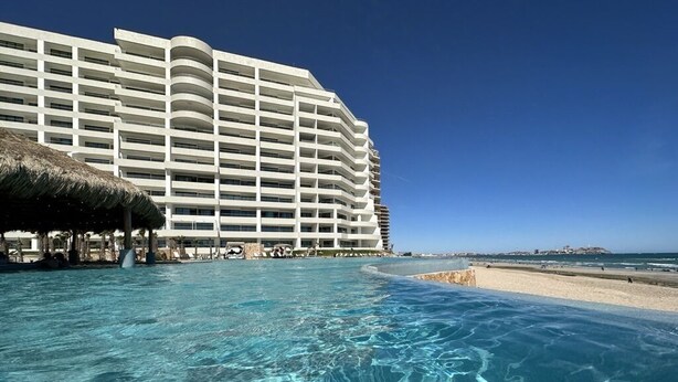 A hotel with a large pool, a beach, and a clear blue sky. - Amazing brand new 2BD/2Bath Penthouse Condo overlooking the beach. (Puerto Peñasco)