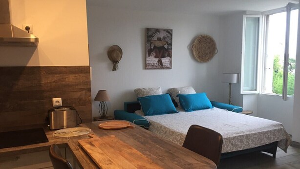 Un dormitorio con una cama, una mesa de madera, una silla, una lámpara y una ventana.