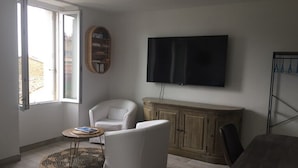 Una sala de estar con un sofá, un sillón y un televisor montado en la pared.