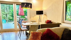 A modern living room with a sofa, a dining table, and a large window.