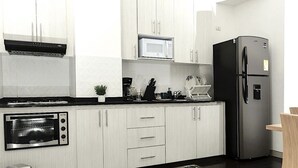 A modern kitchen with white cabinets, a black refrigerator, a microwave, and a built-in oven. - #Apt#Rent#Cali#Imbanaco#Tequendama#Colores#SanFernando#Travel#Colombia#Vacation (Cali)