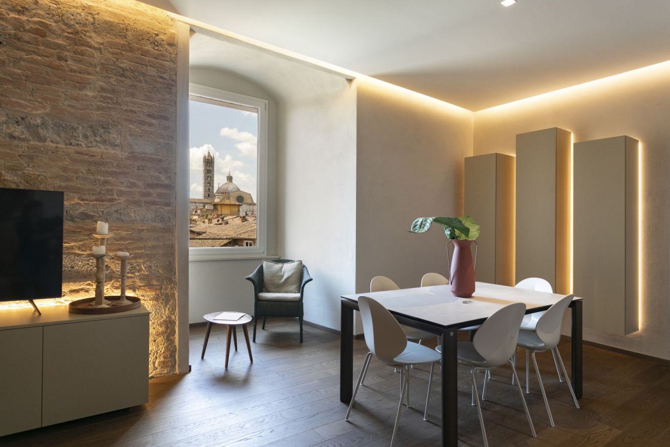 A modern dining area with a table, chairs, and a potted plant.