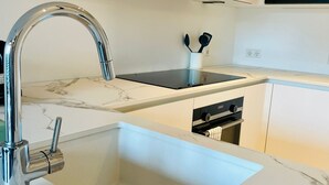 A modern kitchen with a white marble countertop, a stainless steel sink, and a built-in oven. - Large 1 bedroom -Center terrace parking (Luxembourg City)