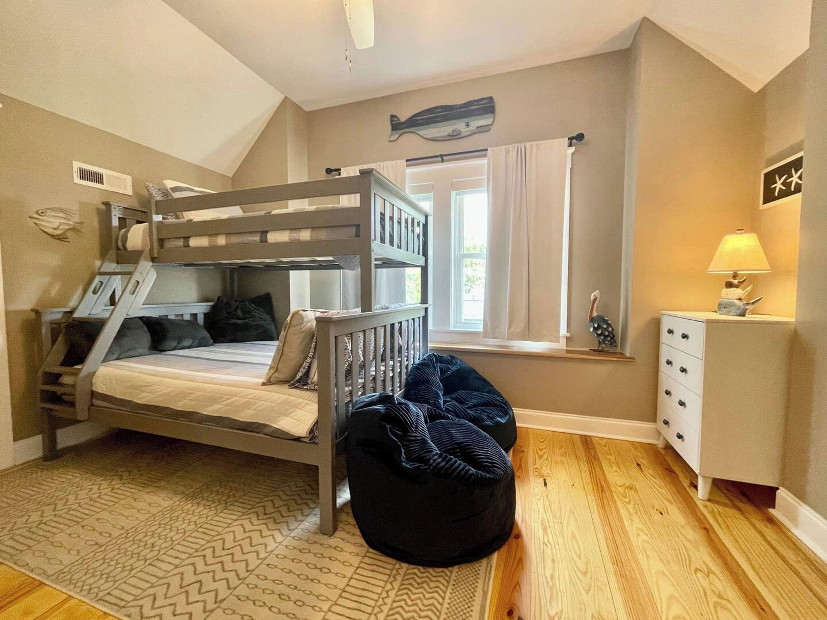 A bunk bed room with a window, a desk, and a lamp.