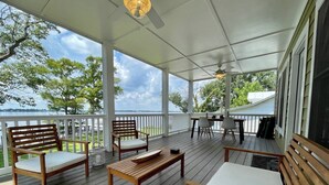 A covered deck with wooden furniture, a table, and chairs.