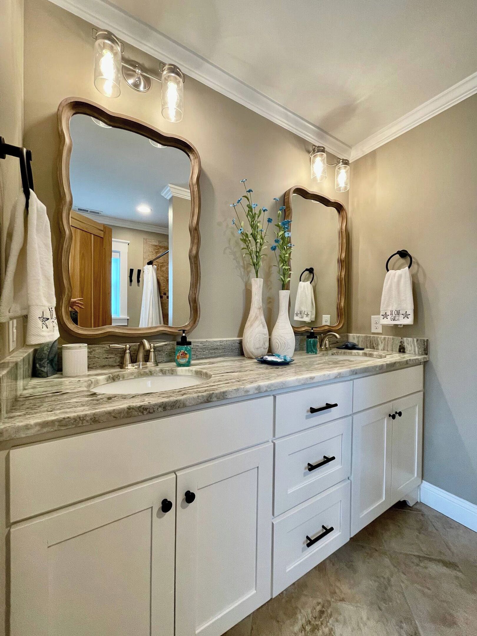 A bathroom with a large vanity, two mirrors, a sink, and a towel rack.