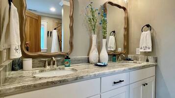 A bathroom with a large vanity, two mirrors, a sink, and a towel rack.