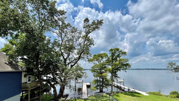 A lakeside property with a dock, a grassy lawn, and a blue building.