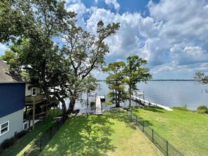 A lakeside property with a dock, a grassy lawn, and a blue building. - New Bern Waterfront Sunset 3 Bedroom Home (New Bern)