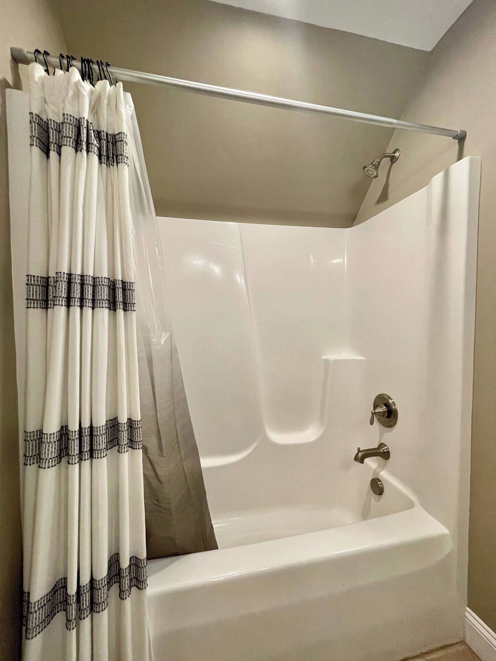 Un baño con bañera, cortina de ducha y barra para cortina.