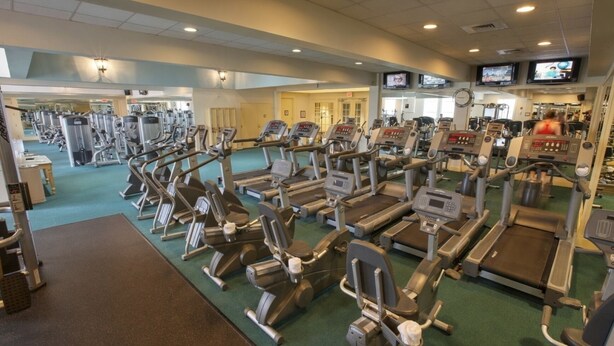 A gym with various exercise machines, including treadmills and elliptical trainers, arranged in rows. - Orlando | Compact Disney Retreat | Pool + Spa (Lake Buena Vista)