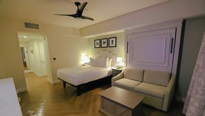 A hotel room with a bed, a sofa, a nightstand, a lamp, and a ceiling fan. - Orlando | Compact Disney Retreat | Pool + Spa (Lake Buena Vista)