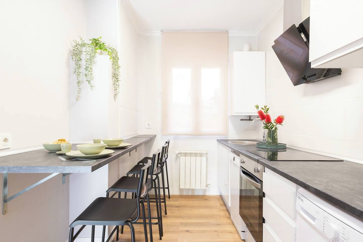 Cocina moderna con una isla central, taburetes de bar y lavavajillas empotrado.