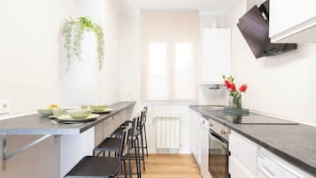 Cocina moderna con una isla central, taburetes de bar y lavavajillas empotrado.