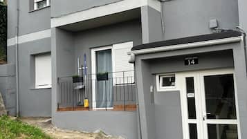Un edificio residencial con fachada gris, un balcón con barandilla negra y una puerta numerada con el número 14.