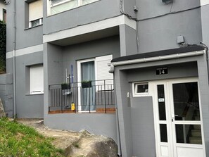 A residential building with a grey facade, a balcony with a black railing, and a door marked with the number 14.