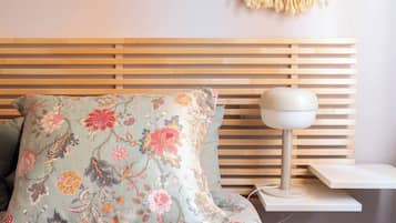 Una cama con un cojín estampado con motivos florales y una mesita de noche con una lámpara.
