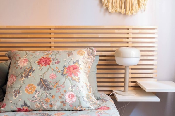 A bed with a floral-patterned pillow and a bedside table with a lamp.