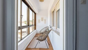 A narrow hallway with large windows, wicker chairs, a rug, and wall-mounted lights. - Casa Surfer Somo centro (Somo)