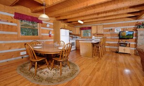A wooden cabin interior with a dining area, kitchen, and a TV. - Paradise #3111 (Gatlinburg)