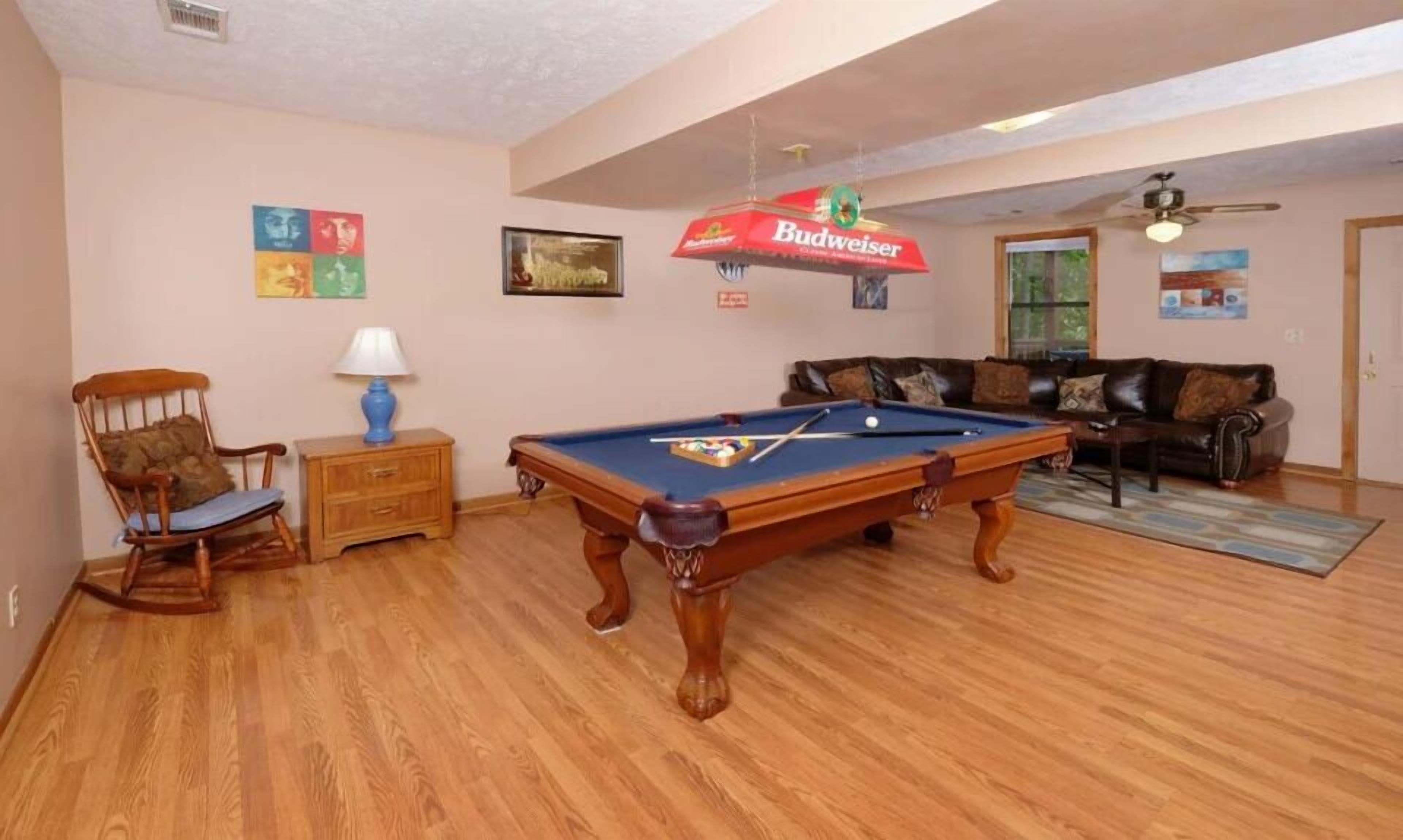 Een kamer met een pooltafel, een houten stoel, een lamp, een bank en een plafondventilator.