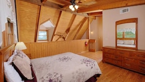 A bedroom with a wooden ceiling, a bed with floral bedding, a dresser, and a window with a view. - Paradise #3111 (Gatlinburg)