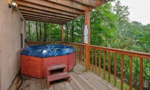 A hot tub on a wooden deck with a wooden railing, surrounded by trees. - Paradise #3111 (Gatlinburg)