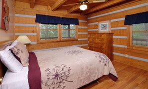 A wooden cabin bedroom with a bed, dresser, and two windows with curtains. - Paradise #3111 (Gatlinburg)