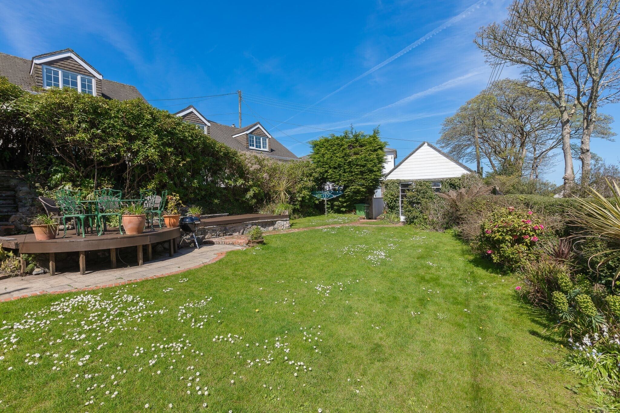 A well-maintained backyard with a lawn, potted plants, and a small patio area.