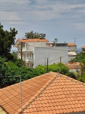 Zona residencial amb una casa amb teulada a dobles vessants i un edifici gris al fons.