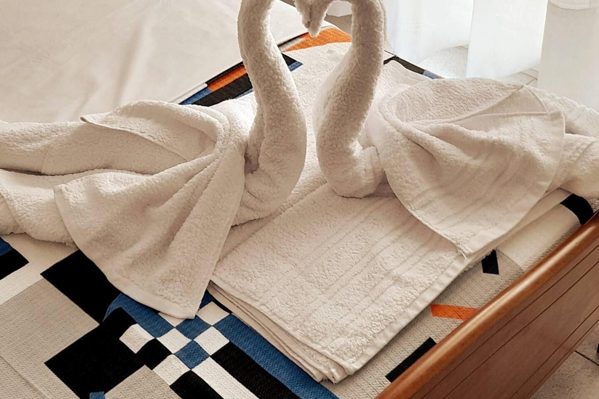 A bed with a white blanket and a checkered blanket on a wooden bed frame.