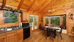A wooden cabin interior with a kitchen, dining area, and large windows. - Country Romance #1279 (Sevierville)