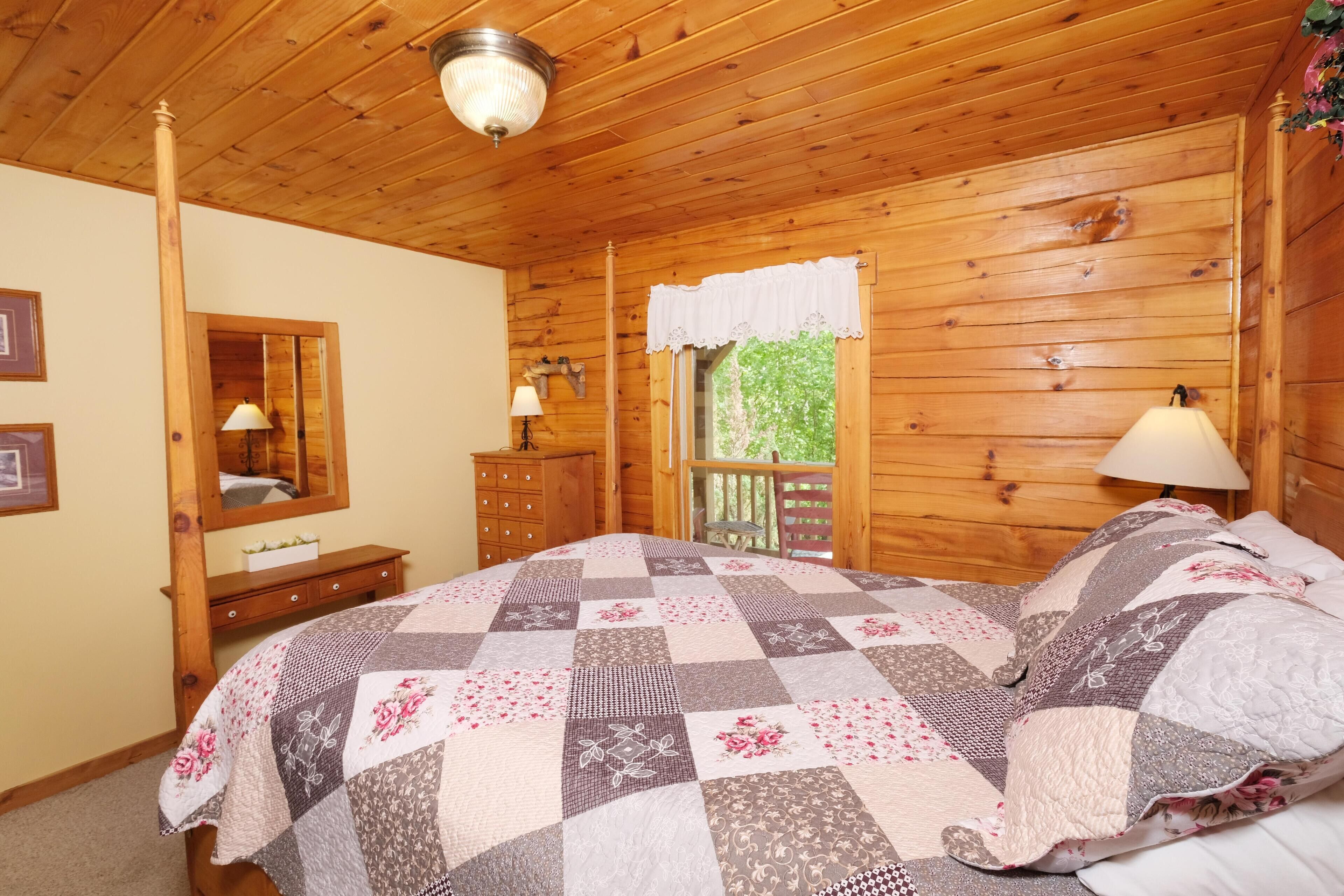 A wooden-paneled bedroom with a bed, dresser, and window with a view.