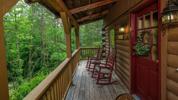 A wooden cabin with a porch, red door, and a view of the forest. - Country Romance #1279 (Sevierville)
