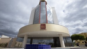 Un hotel moderno con fachada curva, una parte superior cilíndrica destacada y un letrero que dice "NOBLE HOTEL ARARIPINA".