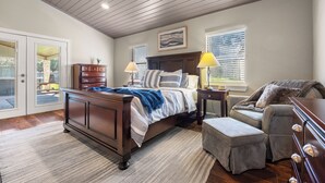 Une chambre à coucher comprenant un lit, des tables de chevet, une chaise et une commode.