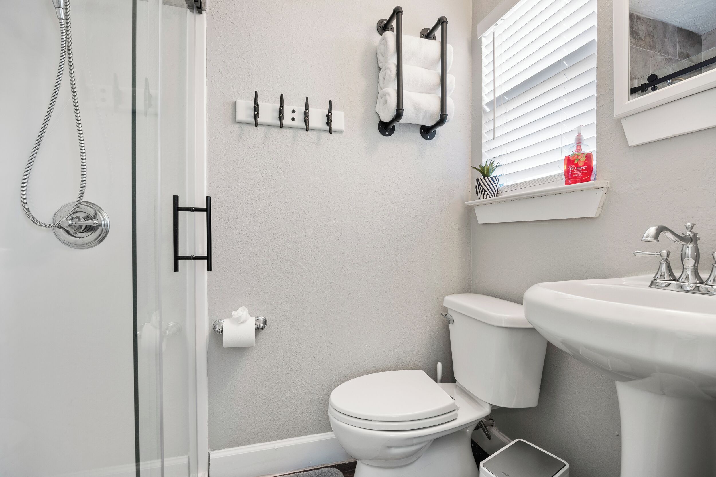 Een badkamer met een douchecabine van glas, een toilet, een wastafel en een handdoekrek.