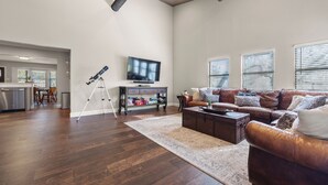 Un salon spacieux avec un canapé en cuir, une table basse et un téléviseur à écran plat fixé au mur.