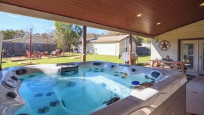 Un bain à remous doté de plusieurs jets, un plafond en bois et une vue sur un jardin avec des meubles d’extérieur.